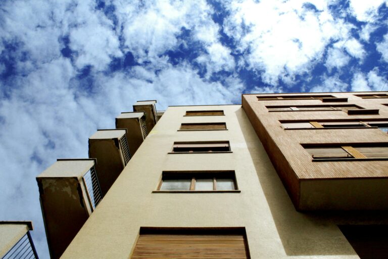 low angle shot of a modern building facade against a vibrant blue sky with clouds. 425343 scaled